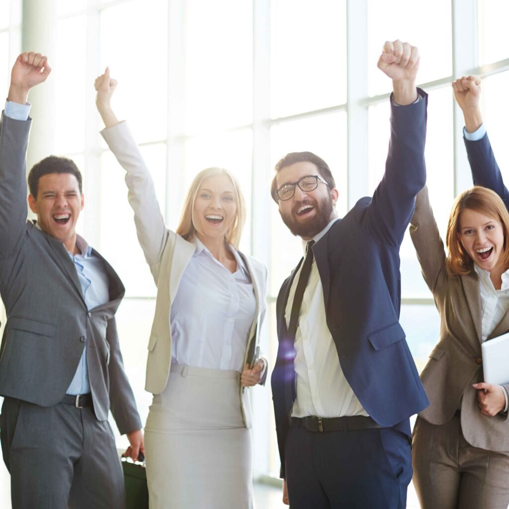 Group of ecstatic business partners looking at camera with raised arms